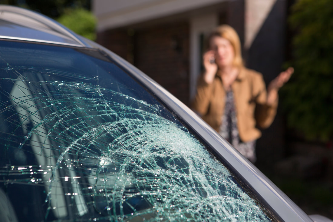 Broken car windshield, woman in the back calling